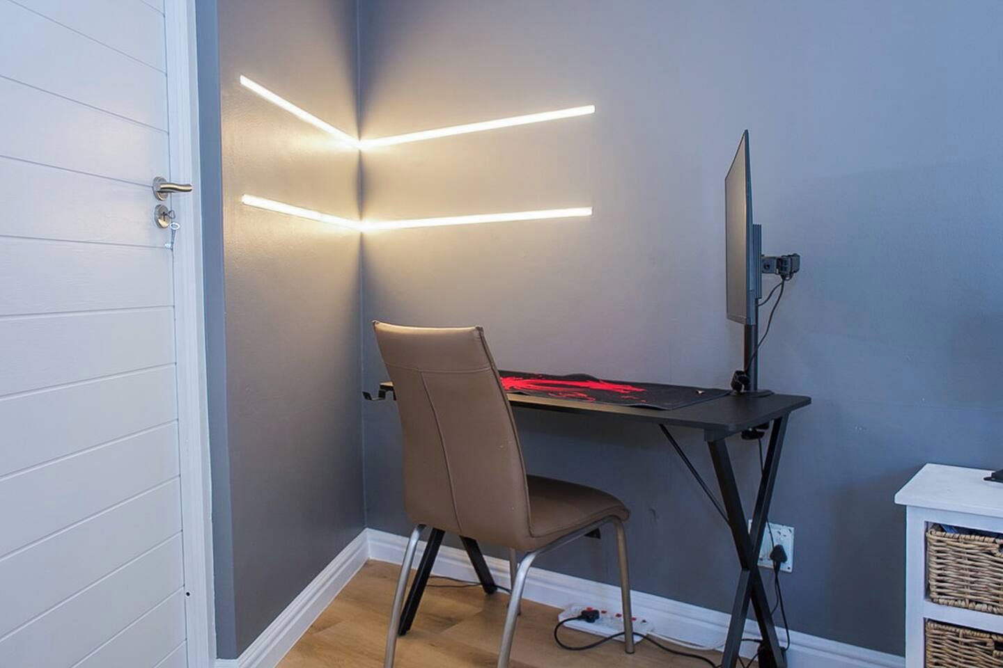 Een hoekappartement met een bureau, stoel en een computerscherm.