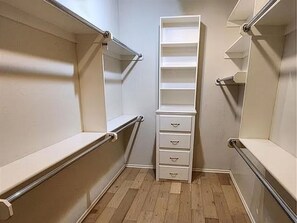 Un vestidor con repisas y cajones integrados, piso de madera y pomos metálicos en las puertas.