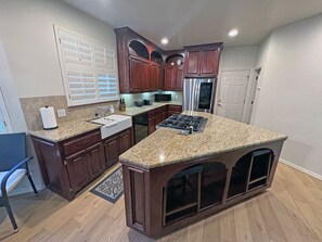 A kitchen with wooden cabinets, a granite countertop, a built-in stove, and a refrigerator.