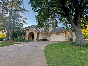A two-story house with a stone facade, a garage, and a driveway leading to the entrance. - Edmond Golf Escape -3BR • 3BA • 4 Beds (Edmond)