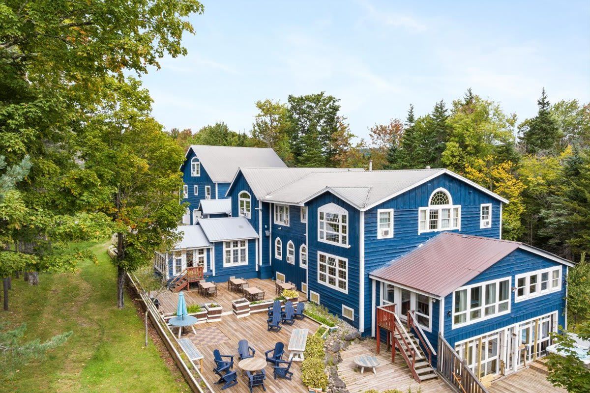 Une grande maison bleue dotée de plusieurs terrasses et d’espaces de détente en plein air.