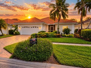 A residential house with a red-tiled roof, a well-maintained lawn, and a mailbox.