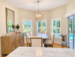 A dining area with a marble table, wooden cabinets, and a chandelier.
