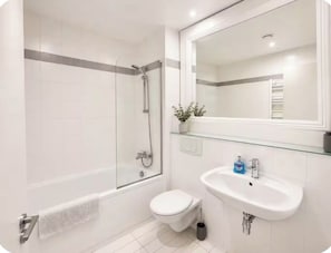A modern bathroom with a glass shower enclosure, a white toilet, a sink with a mirror above it, and a small plant on the sink. - Stylish 2BR | City Centre | Near Northern Quarter (Manchester)