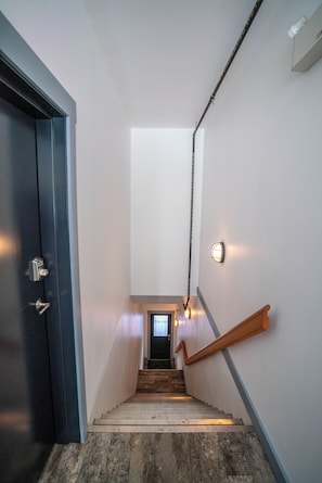 A staircase with a wooden handrail leading to a door with a keypad lock. - Charming 1 bedroom apartment in Downtown Fernie | Walk to Shops & Dining (Fernie)