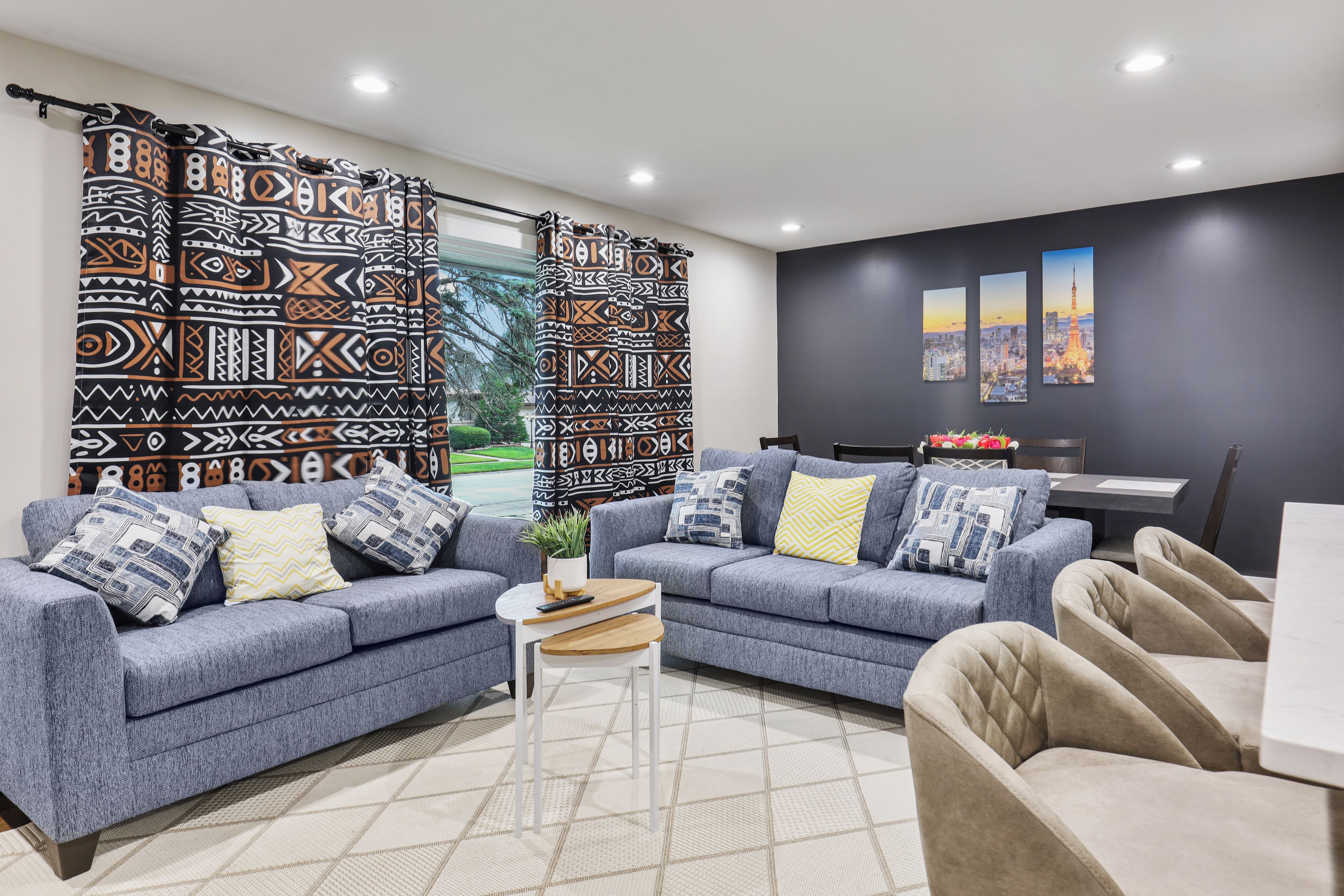 A modern living room with two sofas, a coffee table, and a dining area with a view of the Eiffel Tower.