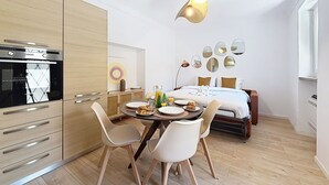 Una habitación de hotel compacta con kitchenette, zona de comedor y cama.