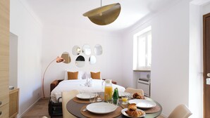 Una habitación de hotel moderna con cama, espacio para el desayuno y una zona de comedor.