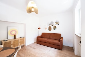 Ein stilvolles Wohnzimmer mit einem braunen Sofa, einem Holzschrank und einer Stehlampe.