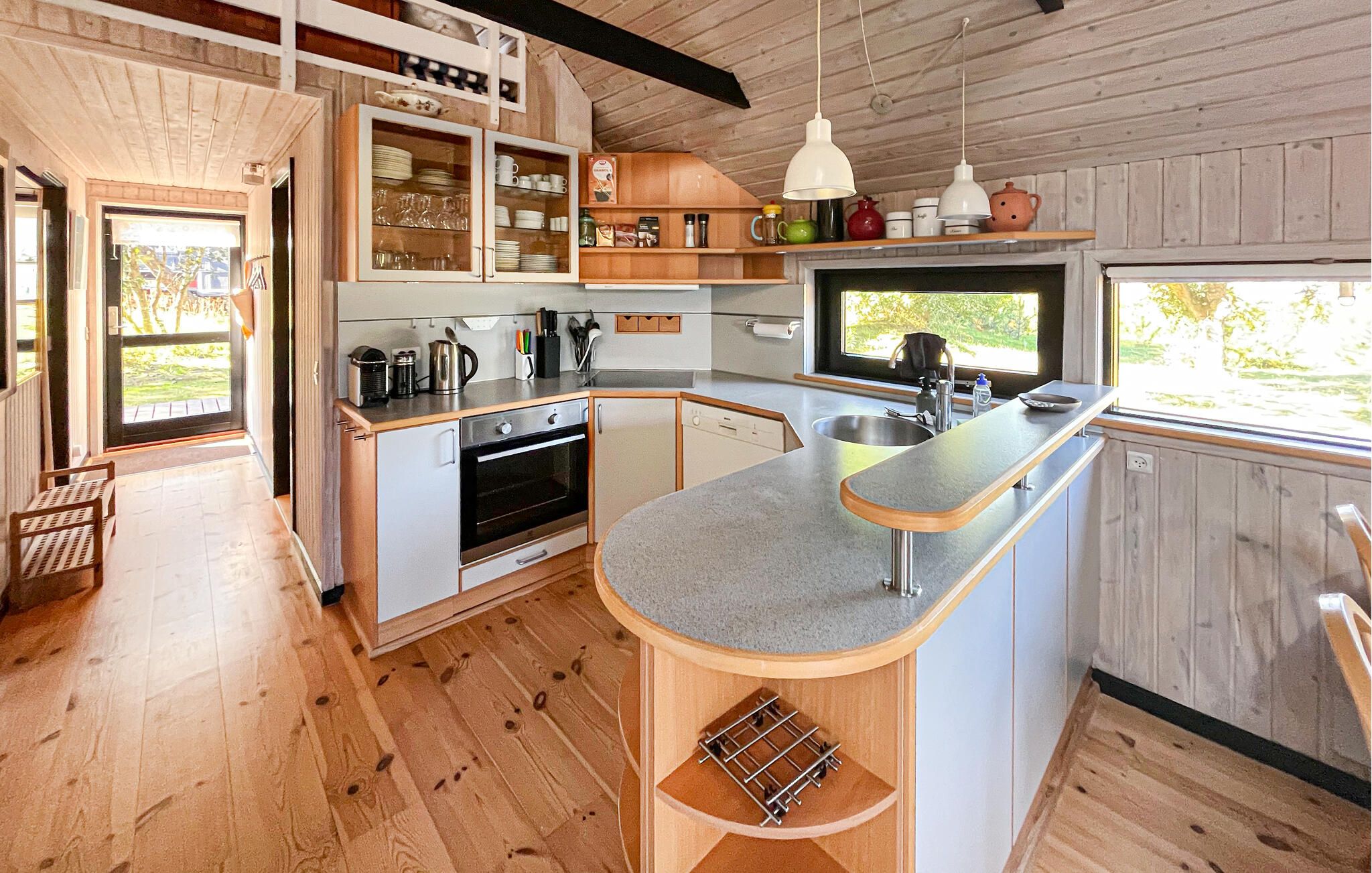 Una cocina moderna con armarios de madera, horno empotrado y un amplio ventanal.