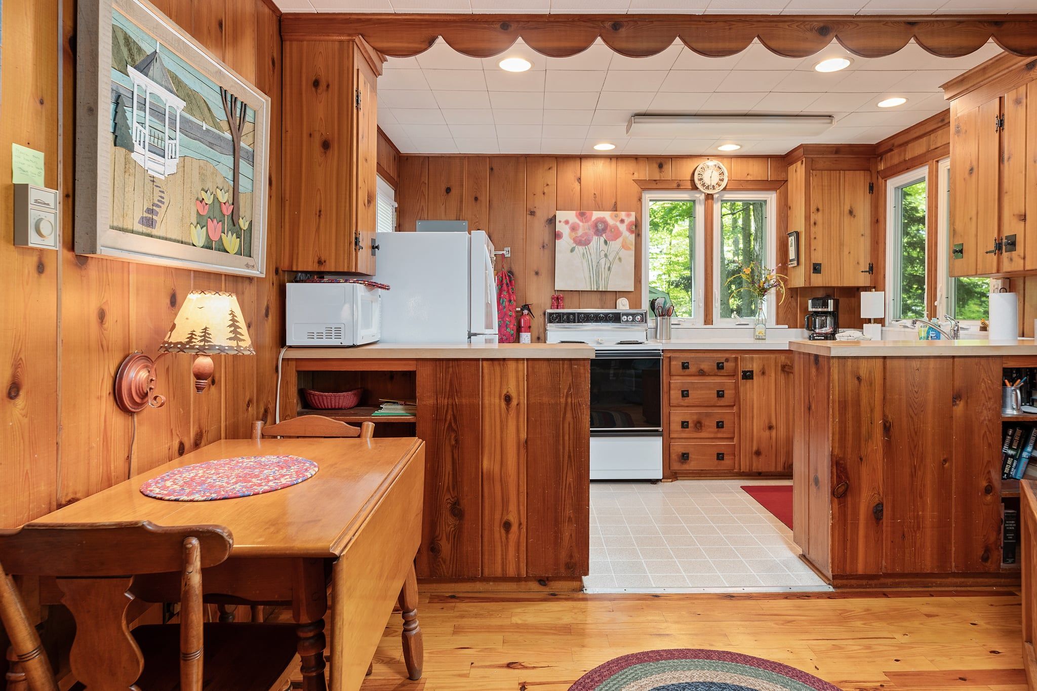 A wooden kitchen with a dining table, a refrigerator, a microwave, and a stove.