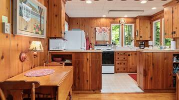 A wooden kitchen with a dining table, a refrigerator, a microwave, and a stove.