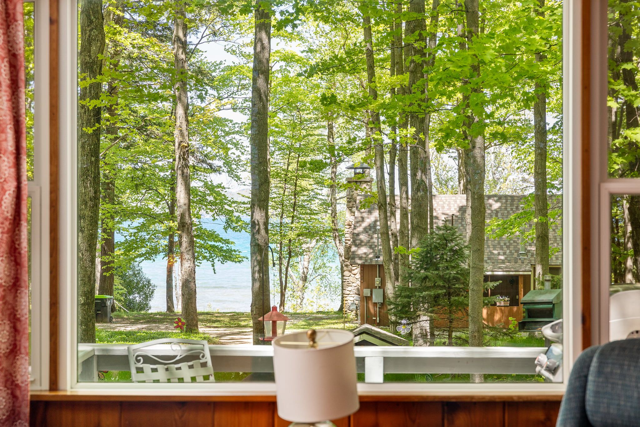 Una ventana con vistas a un bosque y una masa de agua.