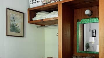 Una camera da letto con un letto, una cassettiera in legno, una sedia e uno specchio.