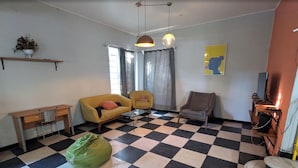 A living room with a checkered floor, a sofa, a chair, a small table, a green bag, and a television. - Villa Luna (Guadalajara)