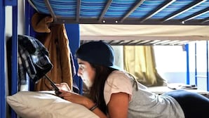 A person lying on a bed in a room with a bunk bed structure, a window with curtains, and a striped ceiling. - Villa Luna (Guadalajara)
