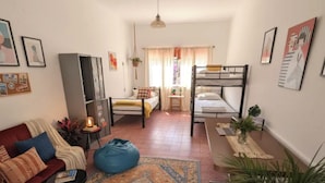 A compact room with a sofa, a small table, a bean bag, a bunk bed, and a desk with a laptop. - Villa Luna (Guadalajara)
