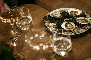 A dining table with a plate of oysters and a glass of white wine.