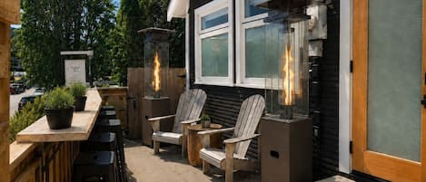 An outdoor seating area with wooden chairs and tables, a bar counter, and a T&PP sign.