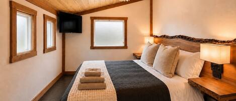 A bedroom with a bed, a television, and a window.