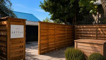 Een privé terras met houten omheining, een bordje met de tekst 'SETTLE' en een metalen poort.