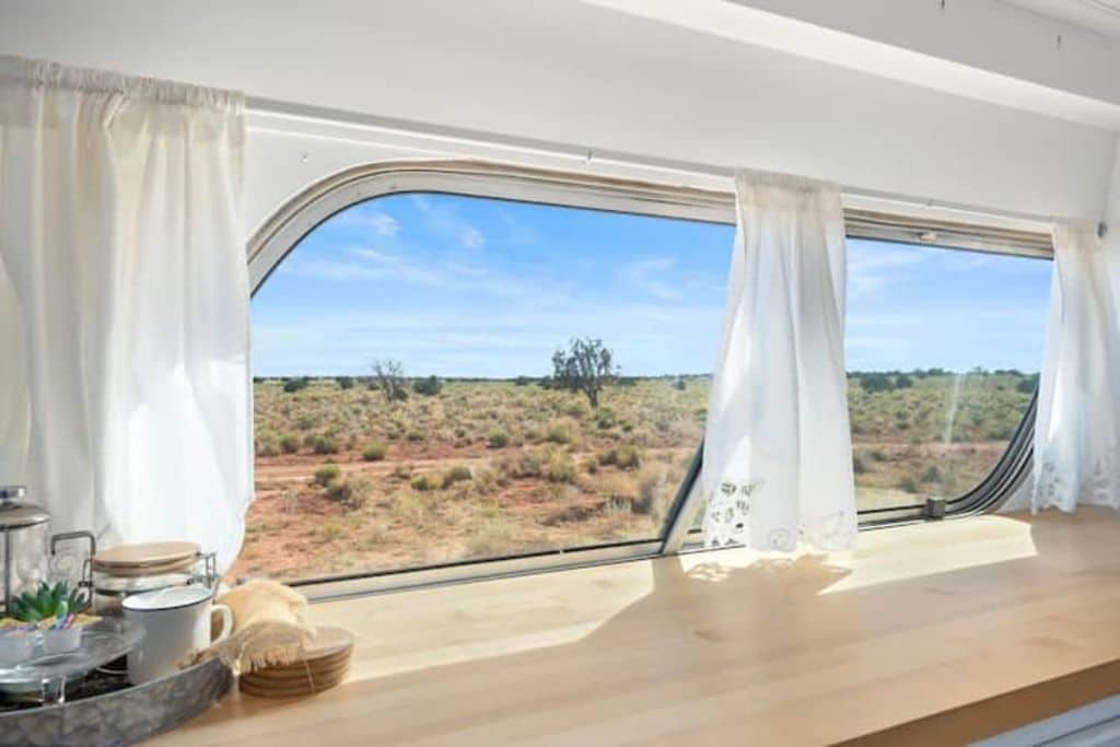 Una habitación con un ventanal grande, una mesa de madera y vistas a un paisaje desértico.