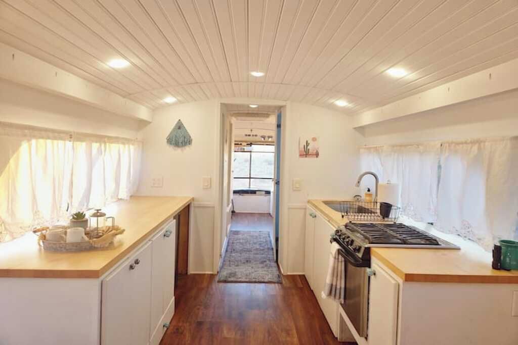 A compact kitchen with wooden cabinets, a stove, and a sink.