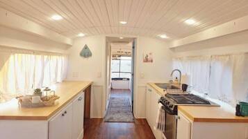 A compact kitchen with wooden cabinets, a stove, and a sink.