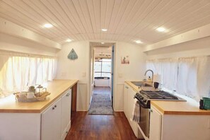 A compact kitchen with wooden cabinets, a stove, and a sink. - Bennie Bus (Williams)