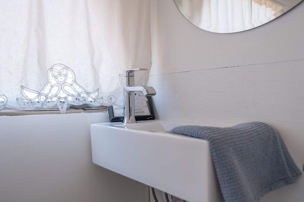 A bathroom with a white sink, a towel, a mirror, and a window with curtains.