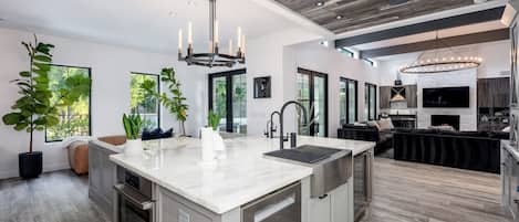 A modern kitchen with a central island, stainless steel appliances, and a large window providing natural light.