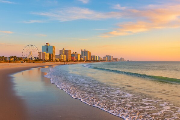 A beach with a city skyline in the background, including a Ferris wheel. - 3BR, 2BA Magnolia Lakes condo in Myrtle Beach, sleeps 6. (Myrtle Beach)