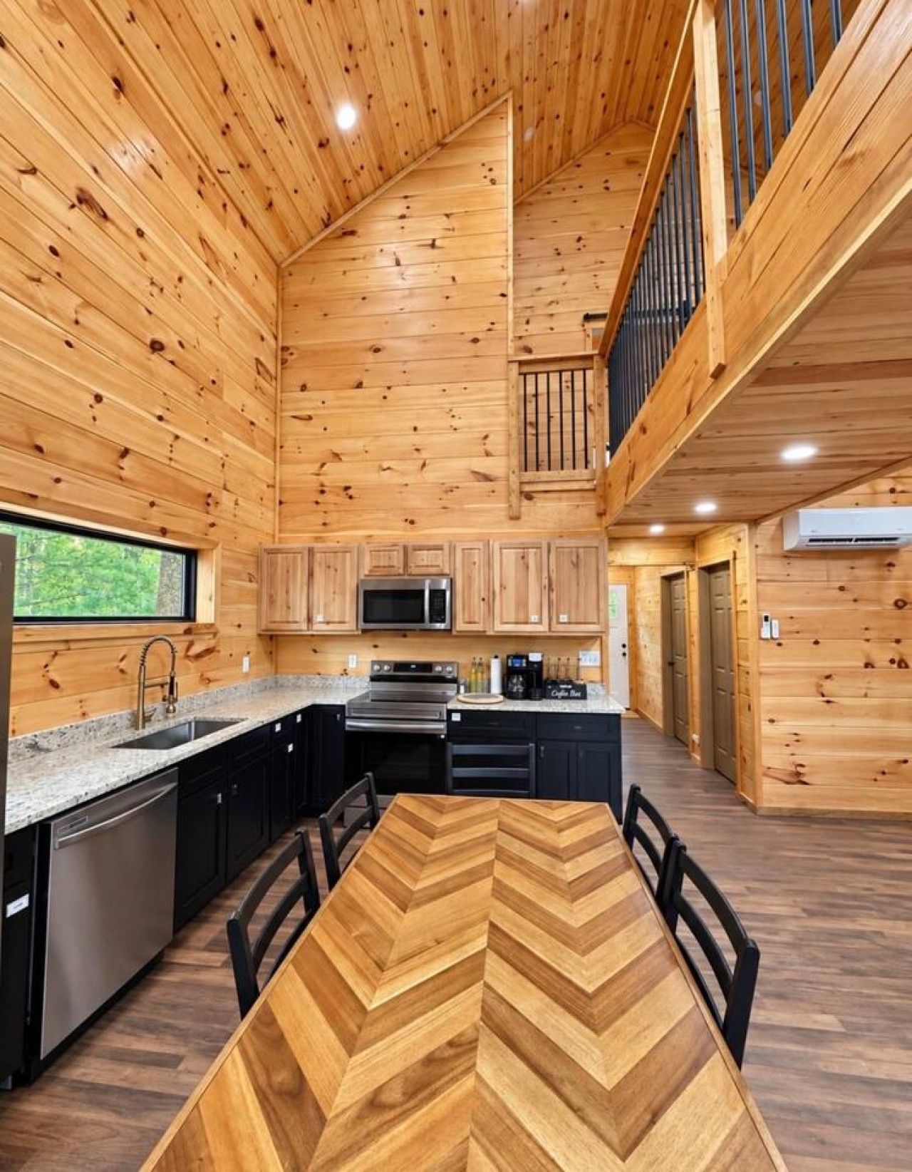 Cozinha moderna com paredes de madeira, uma ilha central e uma área de jantar com mesa em padrão herringbone.