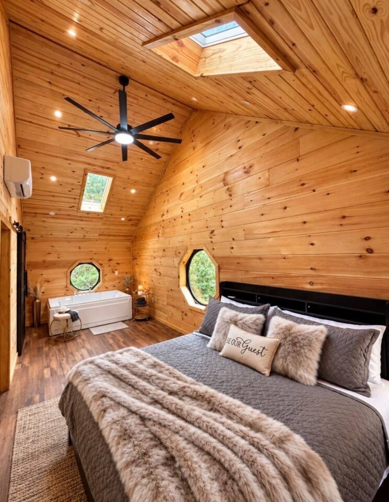 Une chambre confortable avec un grand lit, un ventilateur de plafond et deux fenêtres de toit.