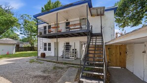 Un edificio residenziale su due piani con un balcone, un garage e un portico.