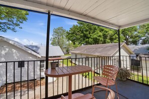 A covered outdoor area with a table and two chairs, a metal railing, and a view of neighboring houses. - Cozy Private Room in Shared Home Near Downtown (Lafayette)