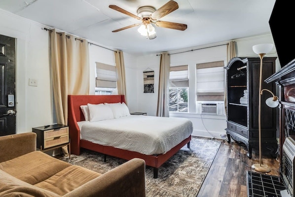 A bedroom with a bed, a nightstand, a dresser, a ceiling fan, and a window.