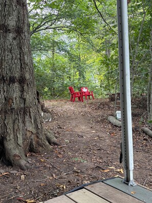A forested area with a metal structure and a red Adirondack chair.