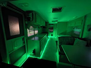 A compact interior with a kitchenette, a small dining area, and a sleeping berth.