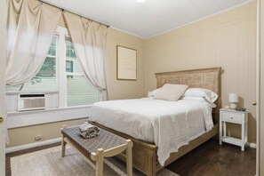 Un dormitorio con cama, mesita de noche, cortinas y un radiador.