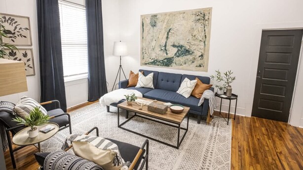 Un salon moderne avec un canapé bleu, une table basse et un grand tableau abstrait accroché au mur.