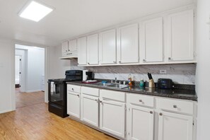 A kitchen with white cabinets, a black stove, and a marble countertop. - Family-Friendly 5BR Lafayette Stay Near Downtown (Lafayette)