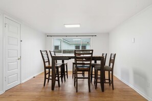 A dining area with a table and chairs, a window with a view of a house, and a white door. - Family-Friendly 5BR Lafayette Stay Near Downtown (Lafayette)