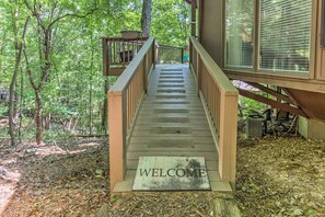 A wooden staircase leading to a deck with a 'WELCOME' mat at the bottom.