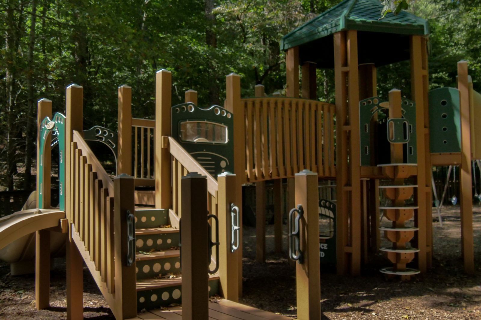 A wooden playground structure with a slide, steps, and climbing areas.