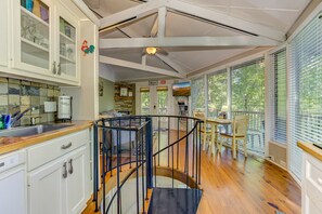 A spacious kitchen with a central island, a dining area with a table and chairs, and a staircase leading to an upper level.