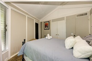 A bedroom with a bed, a wardrobe, a door, and a window with blinds.