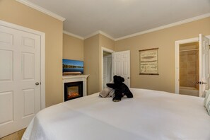 A hotel room with a large bed, a fireplace, a television, and a door leading to a bathroom. - Bear Bluff - Game Room, Fire Table, Comfy Patio + Community Activities (Jasper)