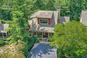 A two-story house with a covered porch, a chimney, and a paved driveway. - Bear Bluff - Game Room, Fire Table, Comfy Patio + Community Activities (Jasper)
