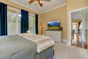 A bedroom with a large bed, a dresser, a television, and a view of a mountain landscape. - Bear Bluff - Game Room, Fire Table, Comfy Patio + Community Activities (Jasper)